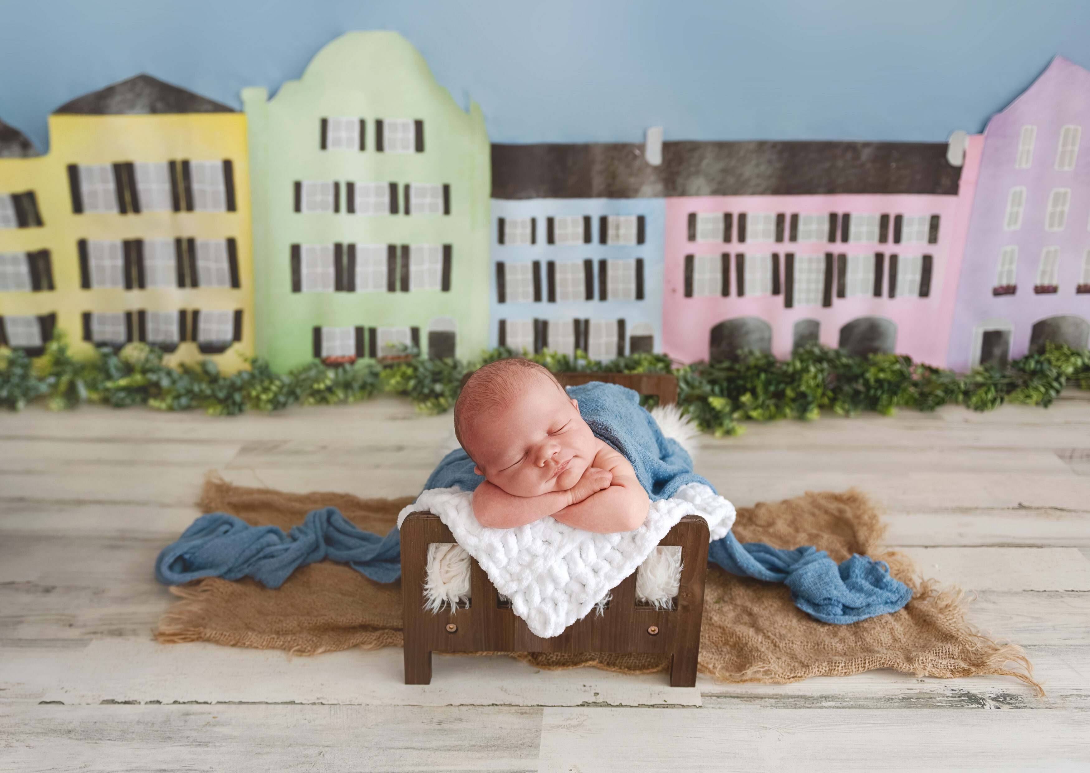 newborn baby boy on brown bed in blue wrap in charleston newborn set